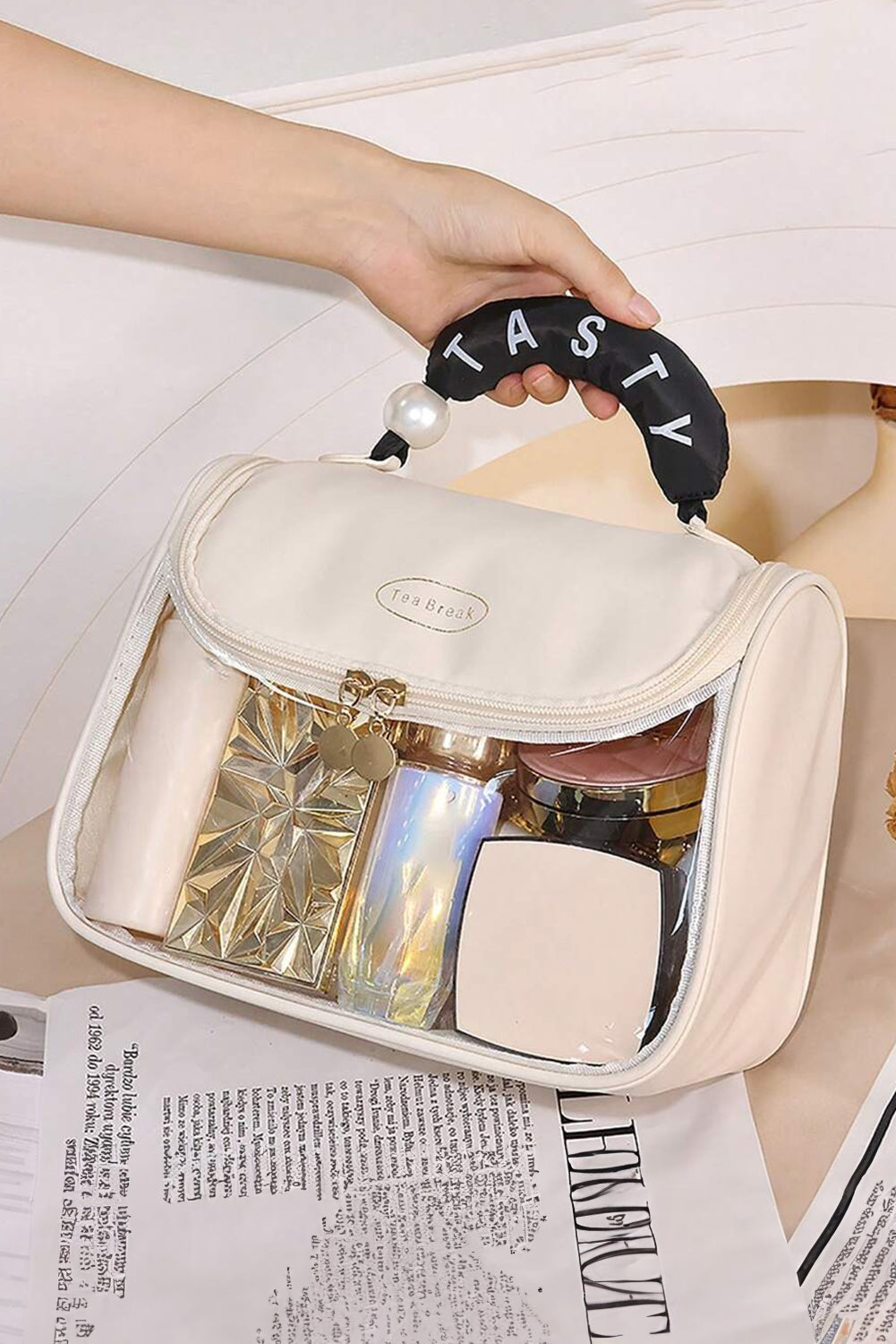 Beige clear makeup bag with TASTY print and handle showing inside pocket for storage