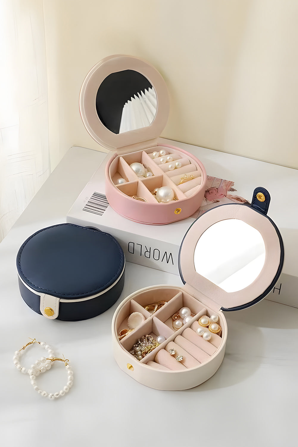 Light pink jewelry organizer cases with mirror and snap button closure, compact and stylish design for easy carrying