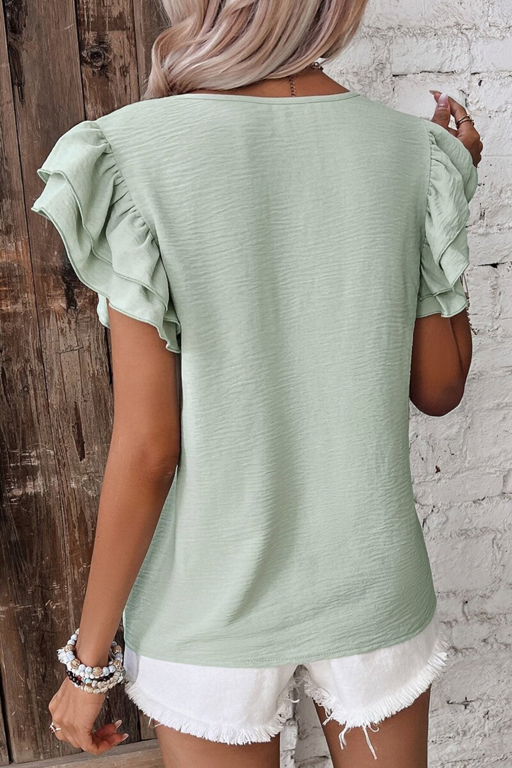 Back view of an aqua ruffled blouse showcasing the stylish short sleeves, perfect for casual outfits.