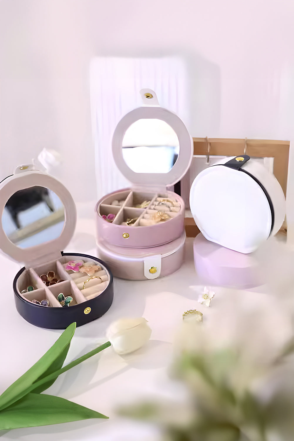 Light pink jewelry organizer case with mirror and snap button closure in compact round shape